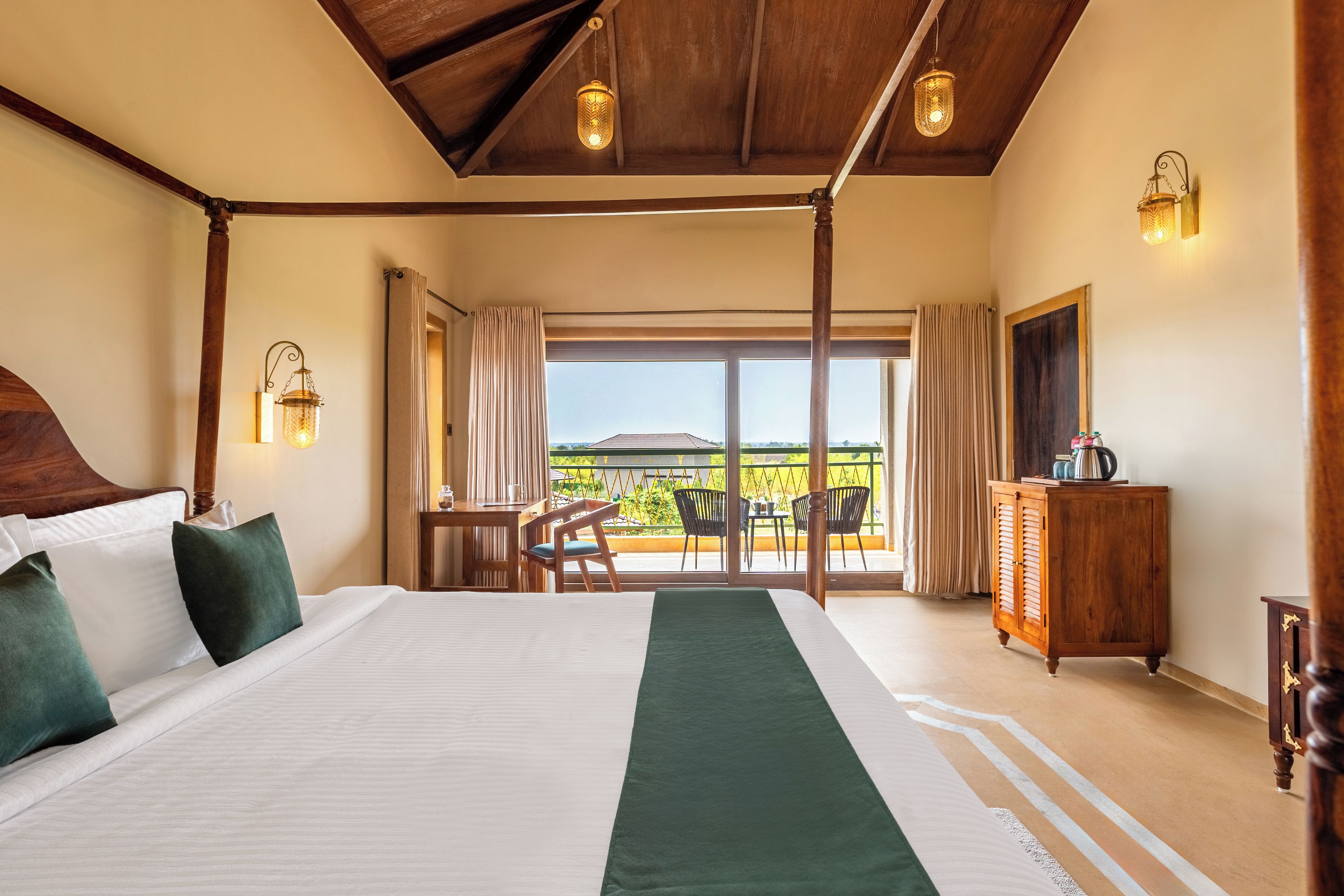 Habitación de hotel con una cama grande, cabecera de madera, balcón con vistas y cómoda de madera.