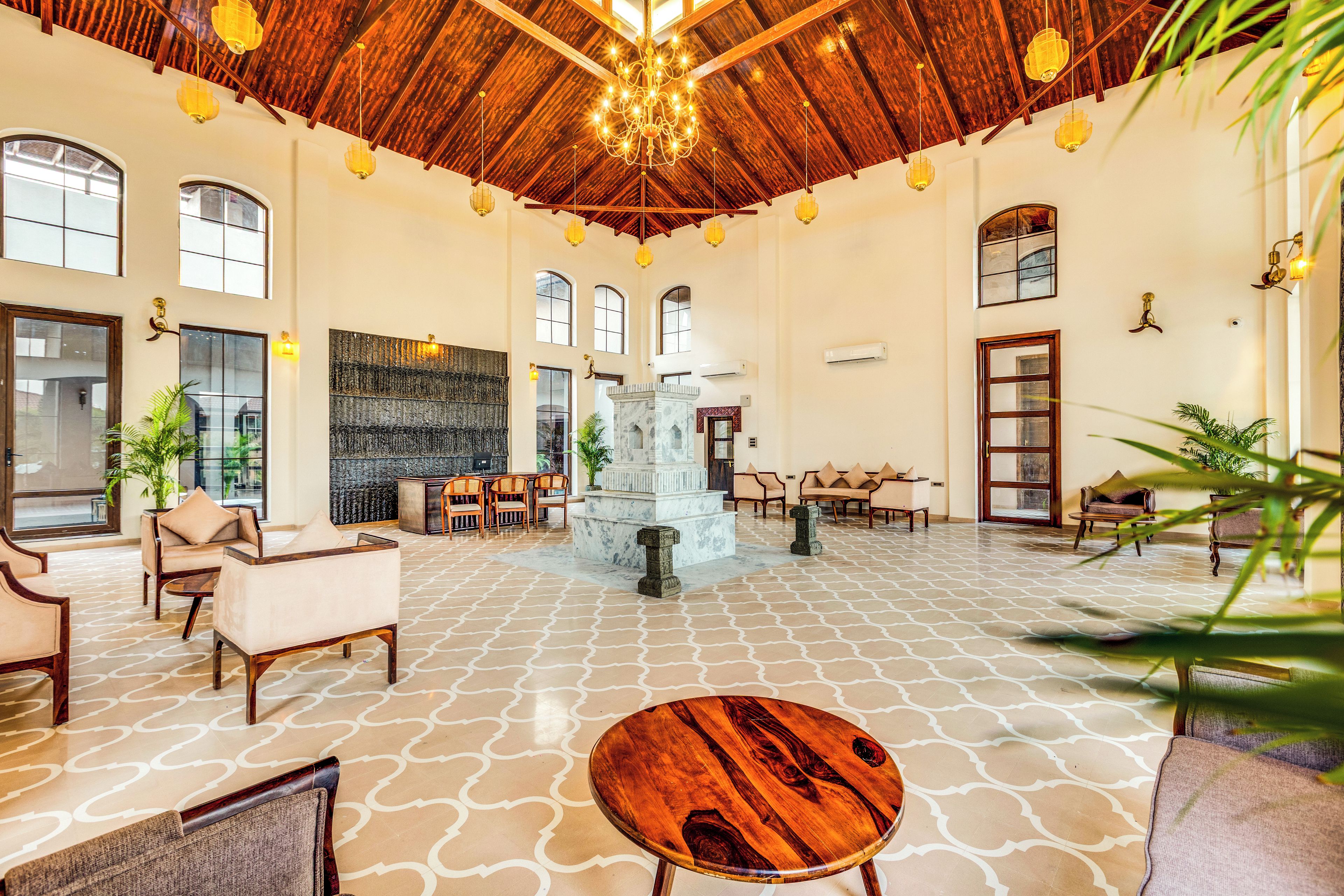 A spacious lobby with a high ceiling, chandeliers, and a central fountain.