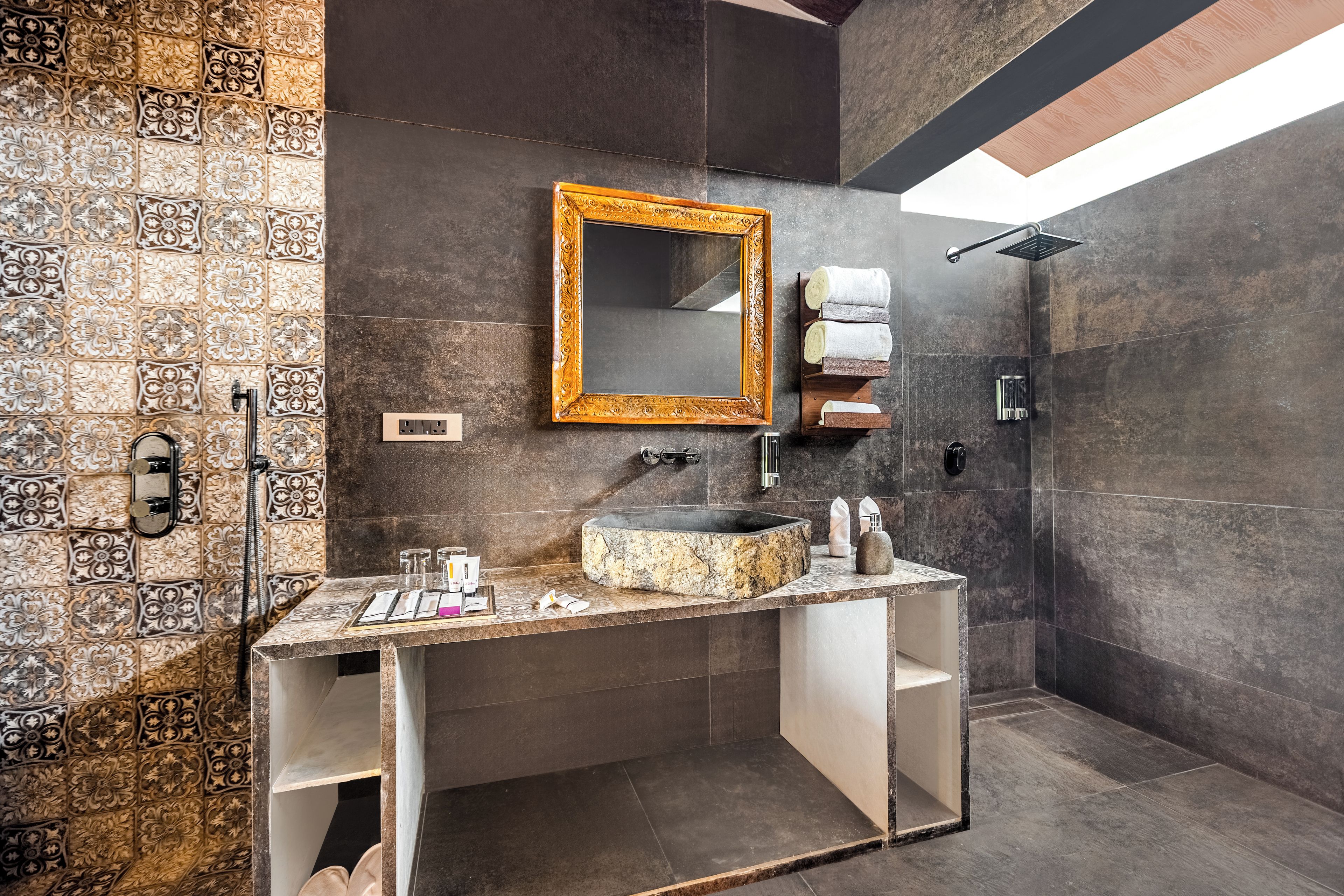 A modern bathroom with a marble sink, a large mirror with an ornate frame, and a shower area.