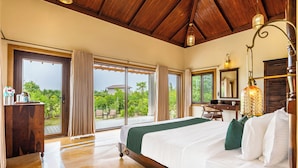 Un dormitorio amplio con una cama grande, un escritorio y vistas al verdor exterior.