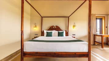 A four-poster bed with a wooden frame, white bedding, and two wall-mounted lamps.
