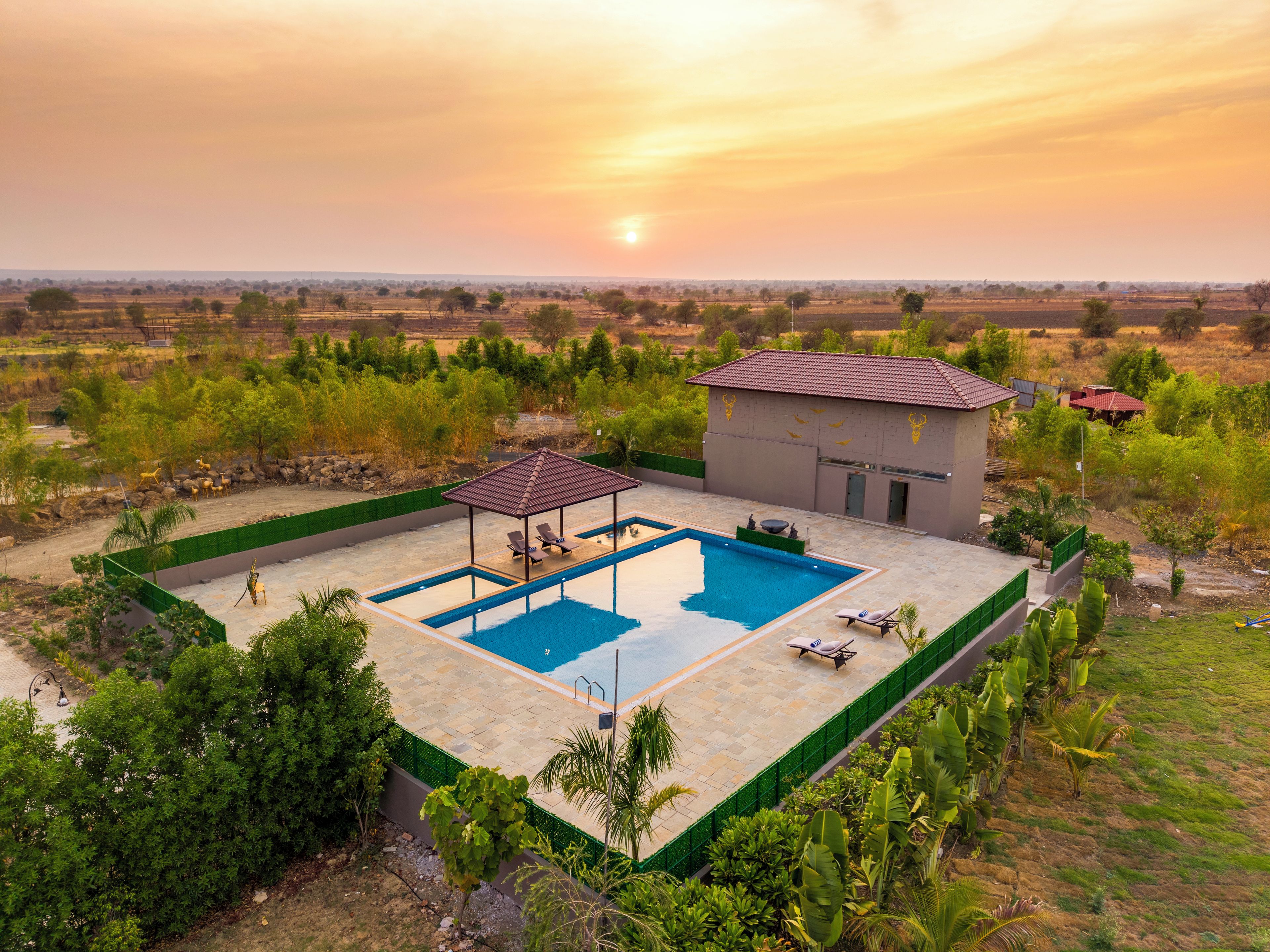 A pool area with a gazebo, lounge chairs, and a small building with a tiled roof.