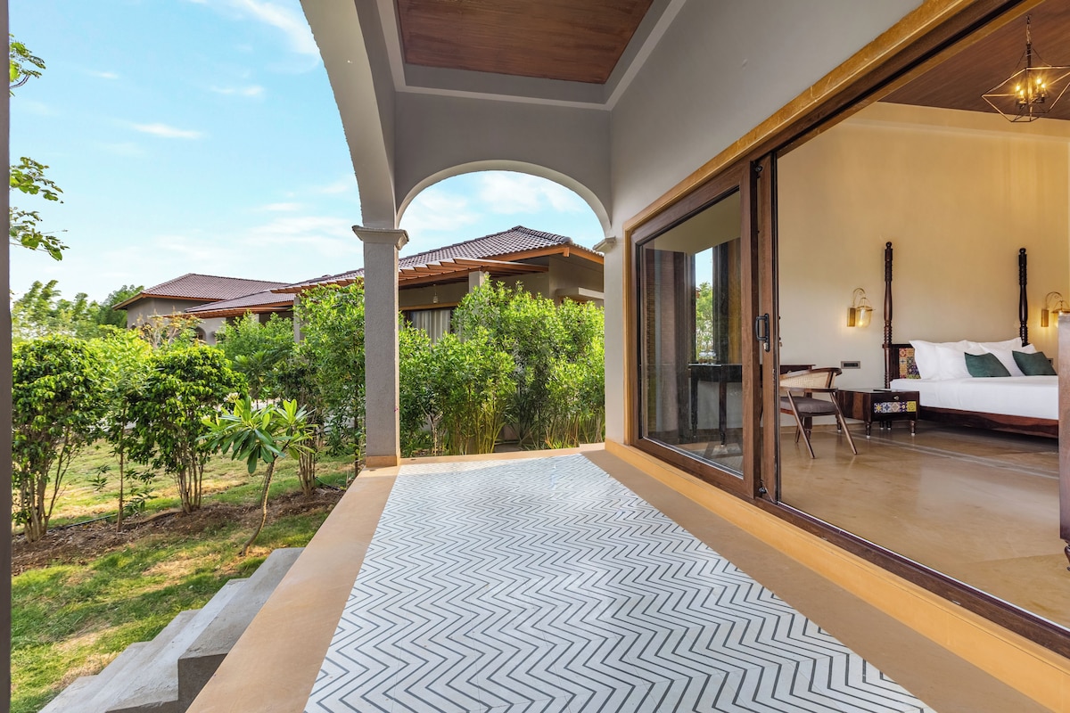 A hotel room with a large sliding glass door leading to a balcony with a patterned floor.
