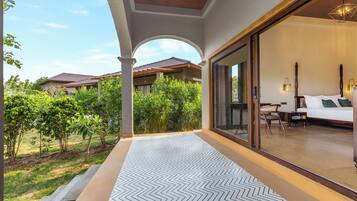 A hotel room with a large sliding glass door leading to a balcony with a patterned floor.