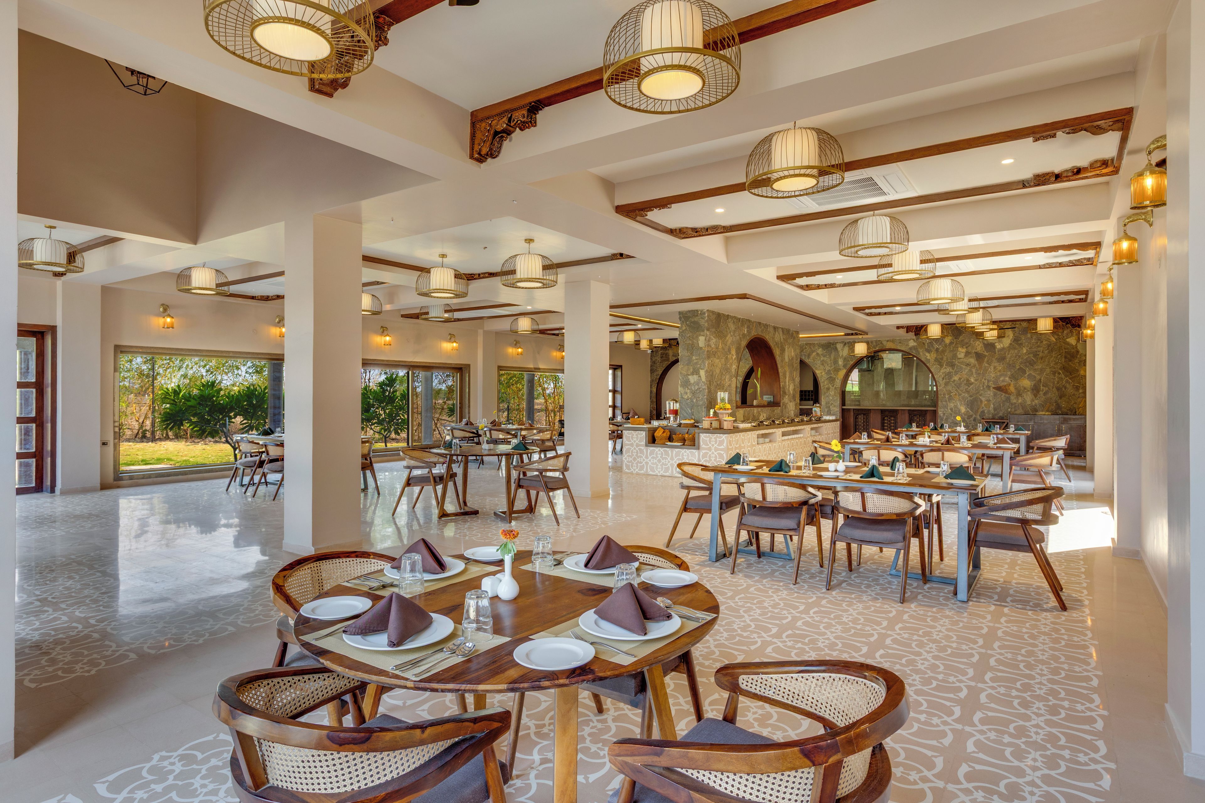 A spacious dining area with multiple tables and chairs, a central bar, and a view of the outdoors.
