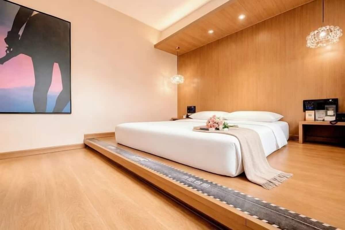 Un dormitorio moderno con una cama, suelo de madera, un cuadro y una mesita de noche.