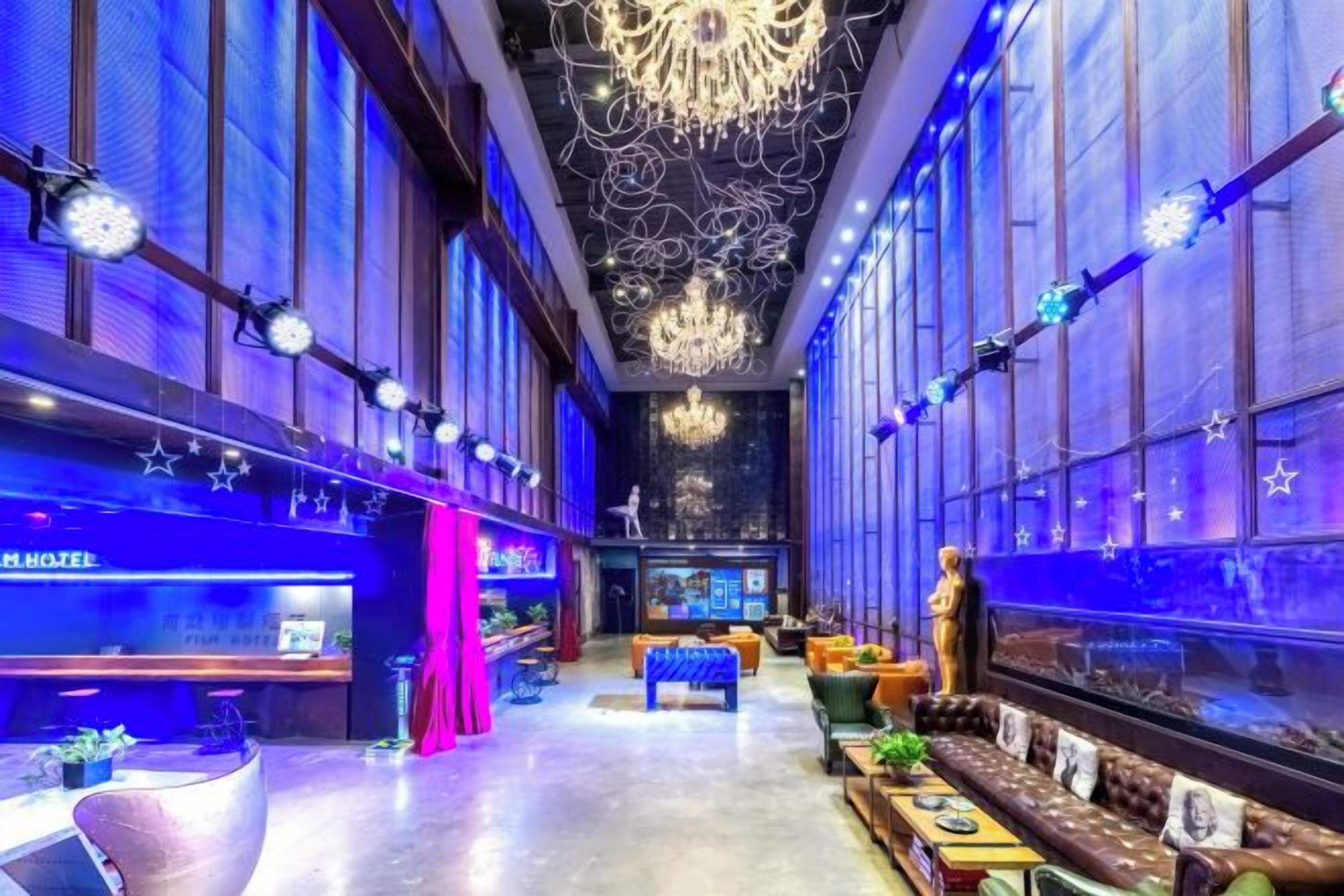 A hotel lobby with a reception desk, seating area, and a chandelier.