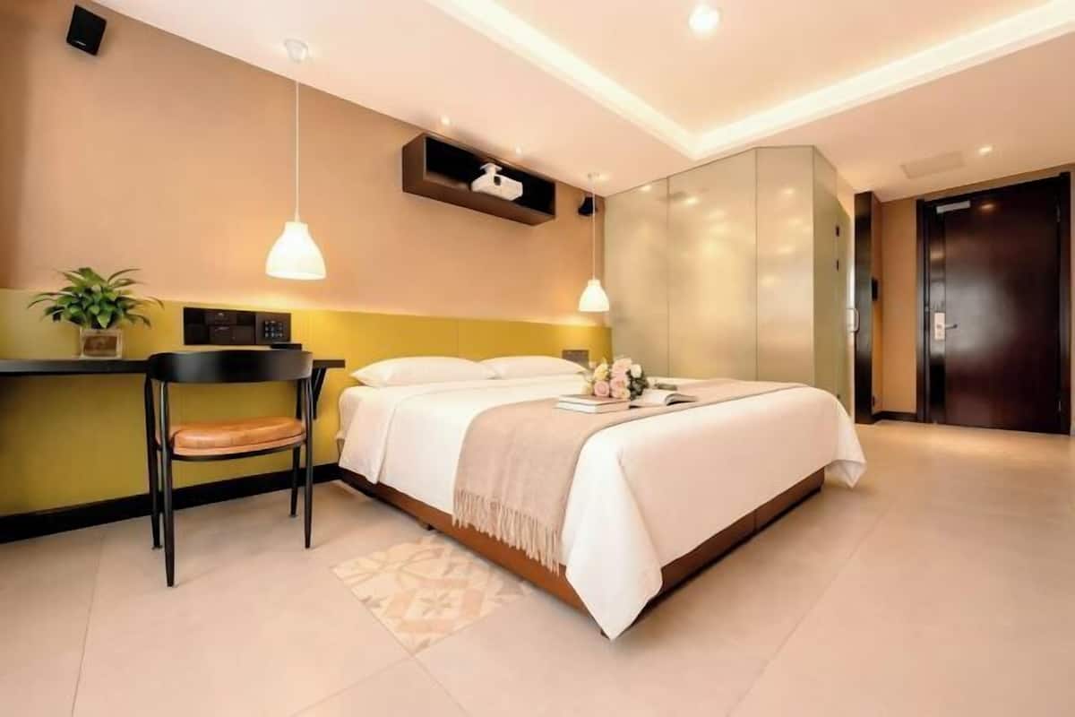 Una habitación de hotel moderna con cama, mesita de noche, silla y escritorio con otra silla.