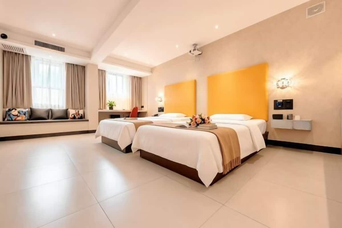Habitación de hotel con dos camas, un ventanal grande y una lámpara fijada a la pared.