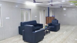 Un área de recepción con un sofá, sillas, una mesa de centro y un mostrador de recepción.