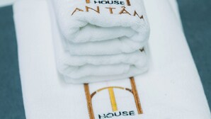 Una pila de toallas blancas con el texto bordado 'HOUSE AN TAM' sobre una superficie azul.