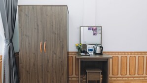 Una habitación con un armario de madera, un escritorio con espejo y un taburete pequeño.