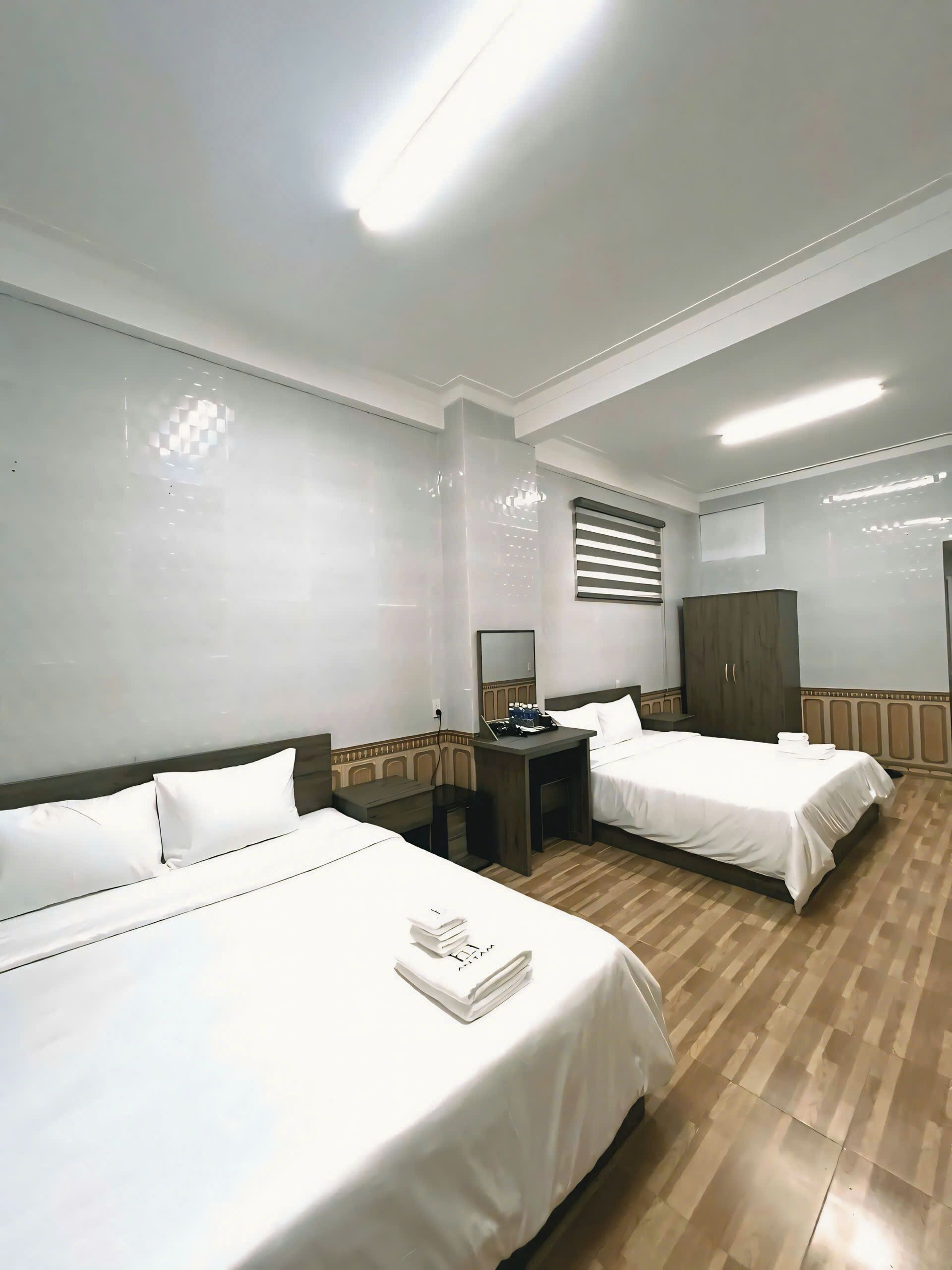 Ein Hotelzimmer mit zwei Betten, einem Schreibtisch, einem Kleiderschrank und einem Spiegel.