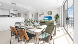 Una cucina moderna con mobili bianchi, un'area pranzo con tavolo apparecchiato per quattro persone e una grande finestra con vista sulla città.