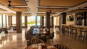 A spacious dining area with high ceilings, large windows, and a view of the outdoors.
