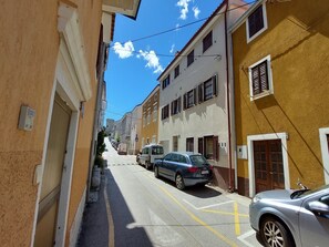 Eine schmale Straße mit parkenden Autos und Häusern an beiden Seiten.