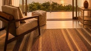 Een kamer met een grote schuifglazen deur die uitkomt op een balkon met uitzicht op een zonsondergang.