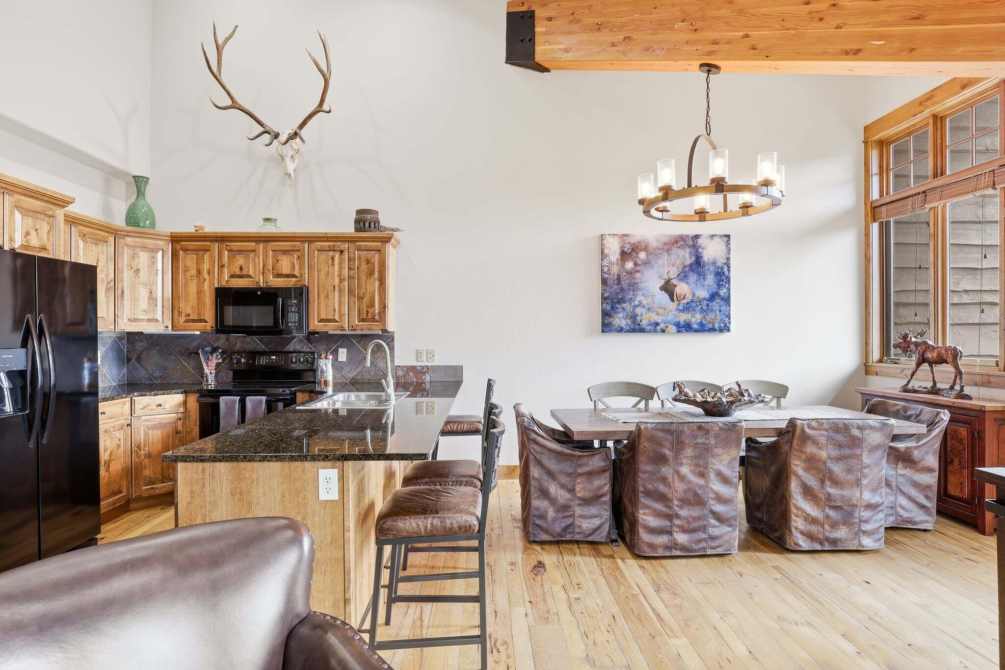 A spacious kitchen with wooden cabinets, a central island, and a dining area with leather chairs.