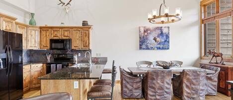 A spacious kitchen with wooden cabinets, a central island, and a dining area with leather chairs.
