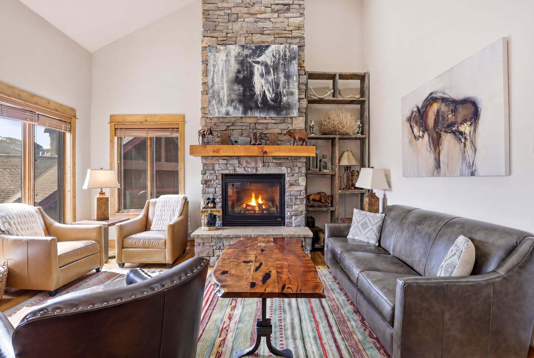 A cozy living room with a stone fireplace, leather furniture, and artwork on the walls.