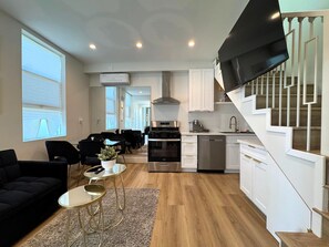 A modern apartment with a dining area, kitchen, and living space.