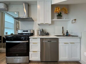 A modern kitchen with white cabinetry, a stainless steel dishwasher, and a black stove.