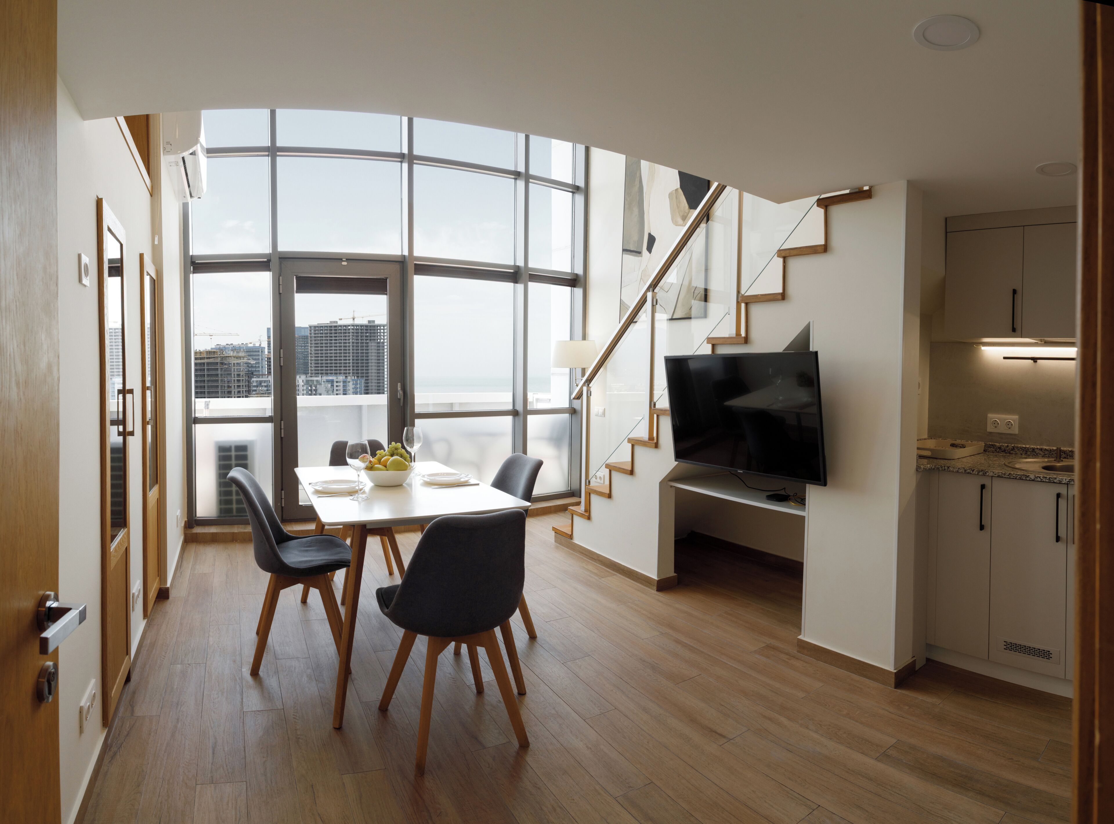 Ein modernes Interieur mit Essbereich, Fernseher und Treppe.