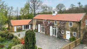 Een gebouw van steen met een rode tegelsdak, een klokkentoren en een geplaveid binnenterrein.