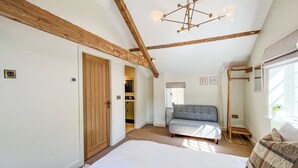 Een slaapkamer met een groot bed, een slaapbank, een houten plafond en een kroonluchter.