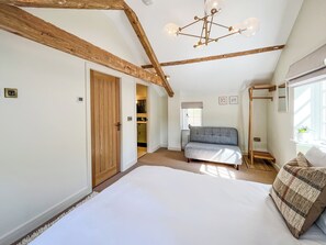 Ein Schlafzimmer mit einem großen Bett, einer Couch, einer Holzzahlendele und einem Kronleuchter.
