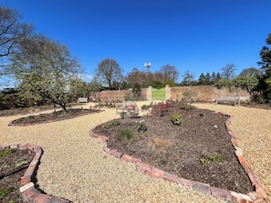 Ein angelegter Garten mit Wegen, Bänken und einer Backsteinmauer.