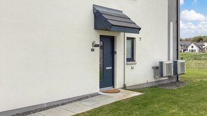 Ein modernes Gebäude mit einer dunkelblauen Tür, einem kleinen Fenster und zwei Klimaanlagen an der Seite.