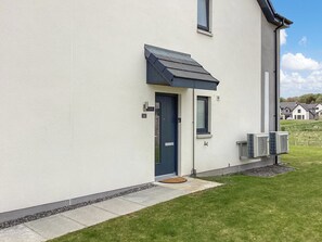 Ein modernes Gebäude mit einer dunkelblauen Tür, einem kleinen Fenster und zwei Klimaanlagen an der Seite.