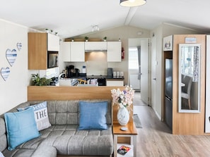 A modern living room with a sofa, a coffee table, and a TV. - 2 bedroom accommodation in Paignton (Paignton)