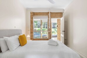 Ein Hotelzimmer mit Bett, Fenster, Tür und Blick ins Freie.