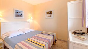 Habitación de hotel con cama, dos mesitas de noche, un escritorio con silla y un espejo.