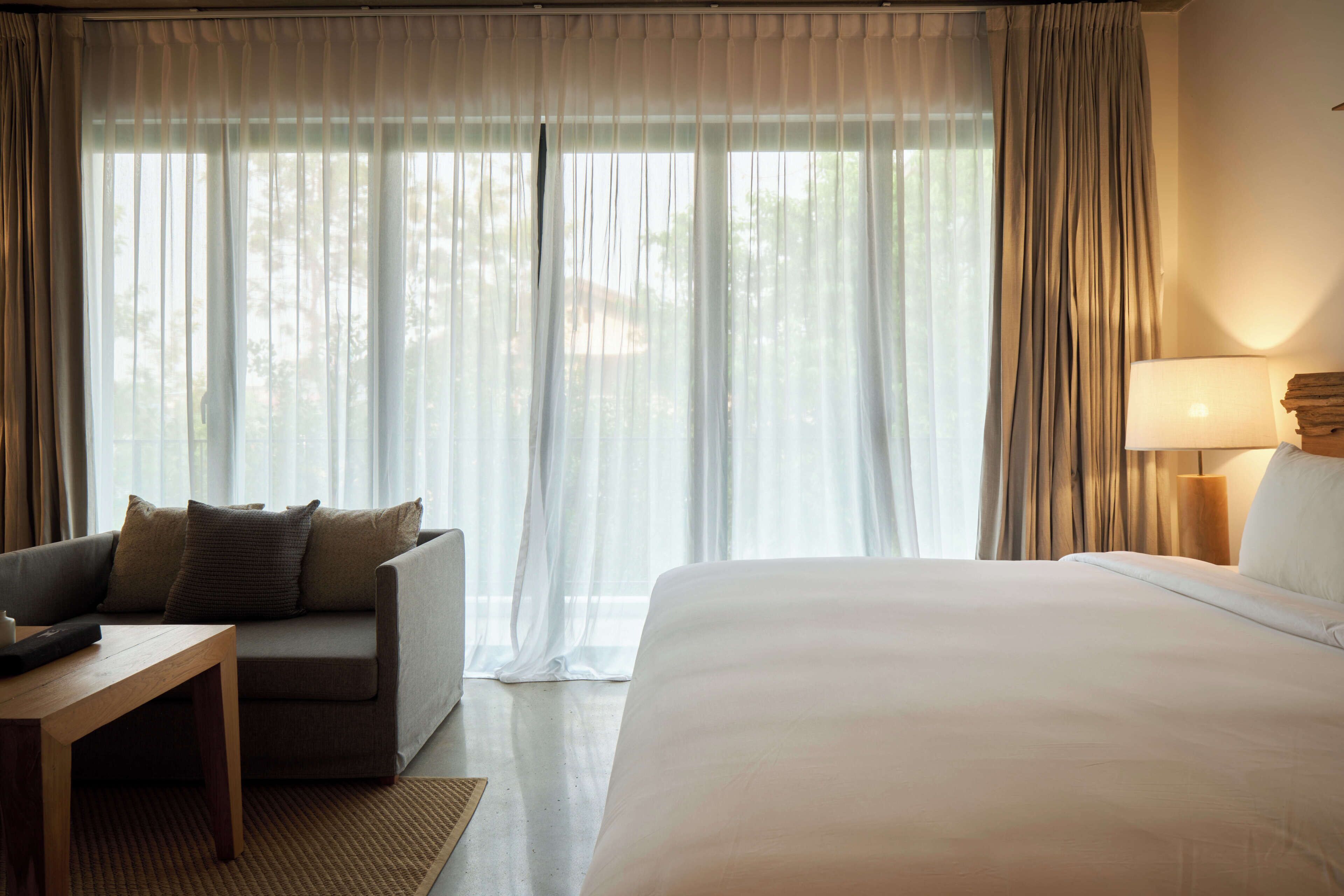 Una habitación de hotel con cama, sofá, mesa y lámpara.