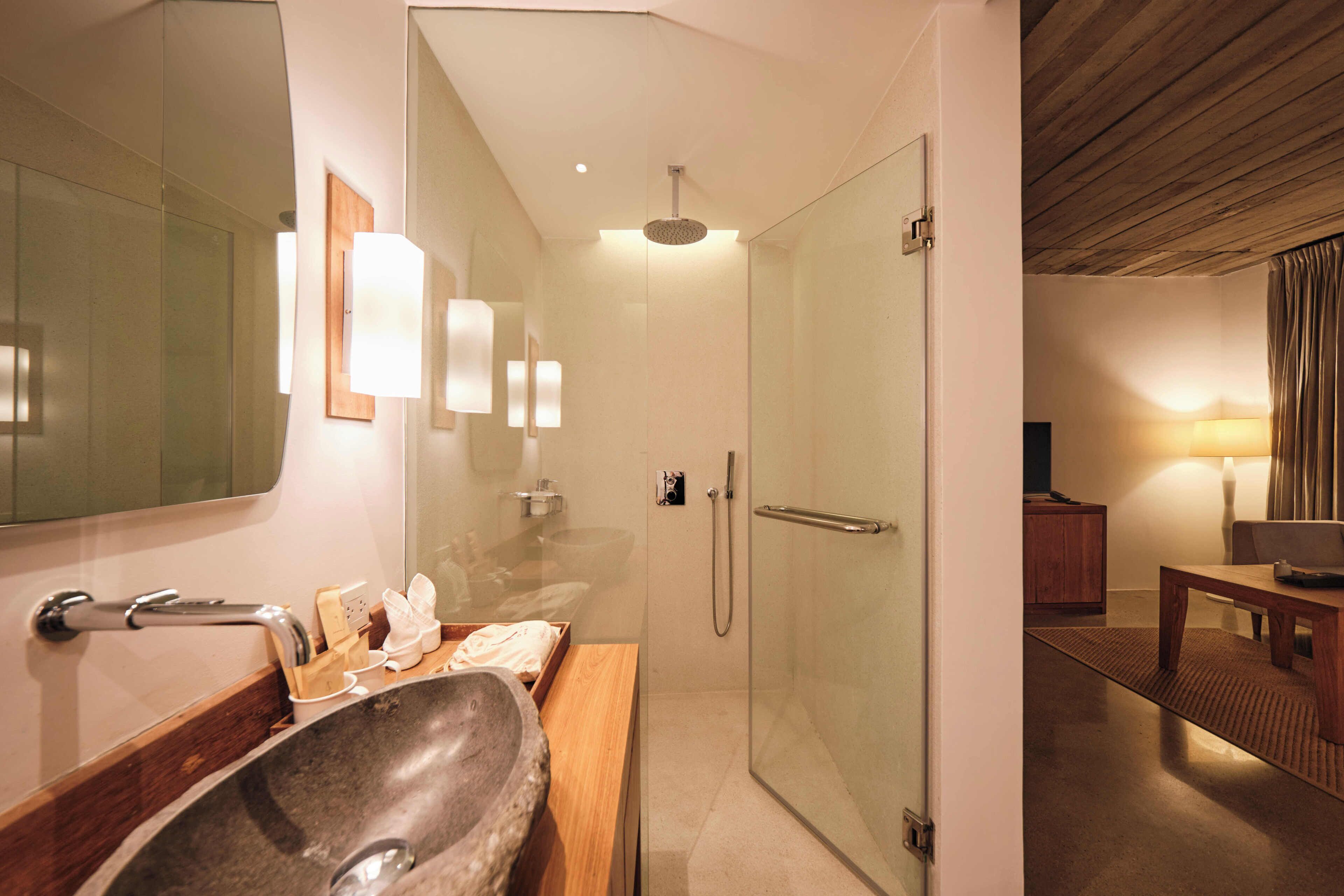 A modern bathroom with a stone sink, glass shower enclosure, and a wooden vanity.