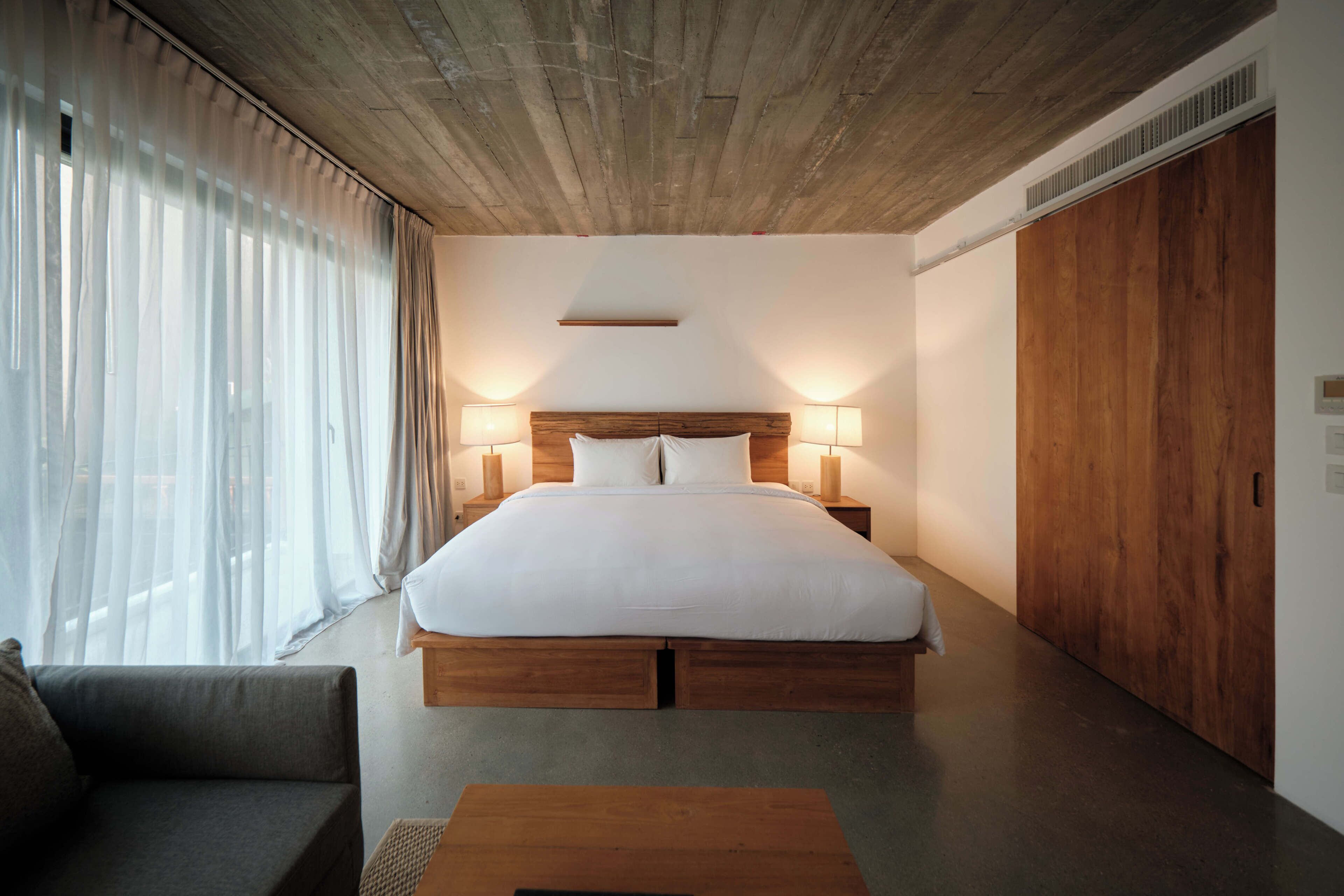 Un dormitorio moderno con una cama grande, cabecero de madera, lámparas de noche y un armario de madera.