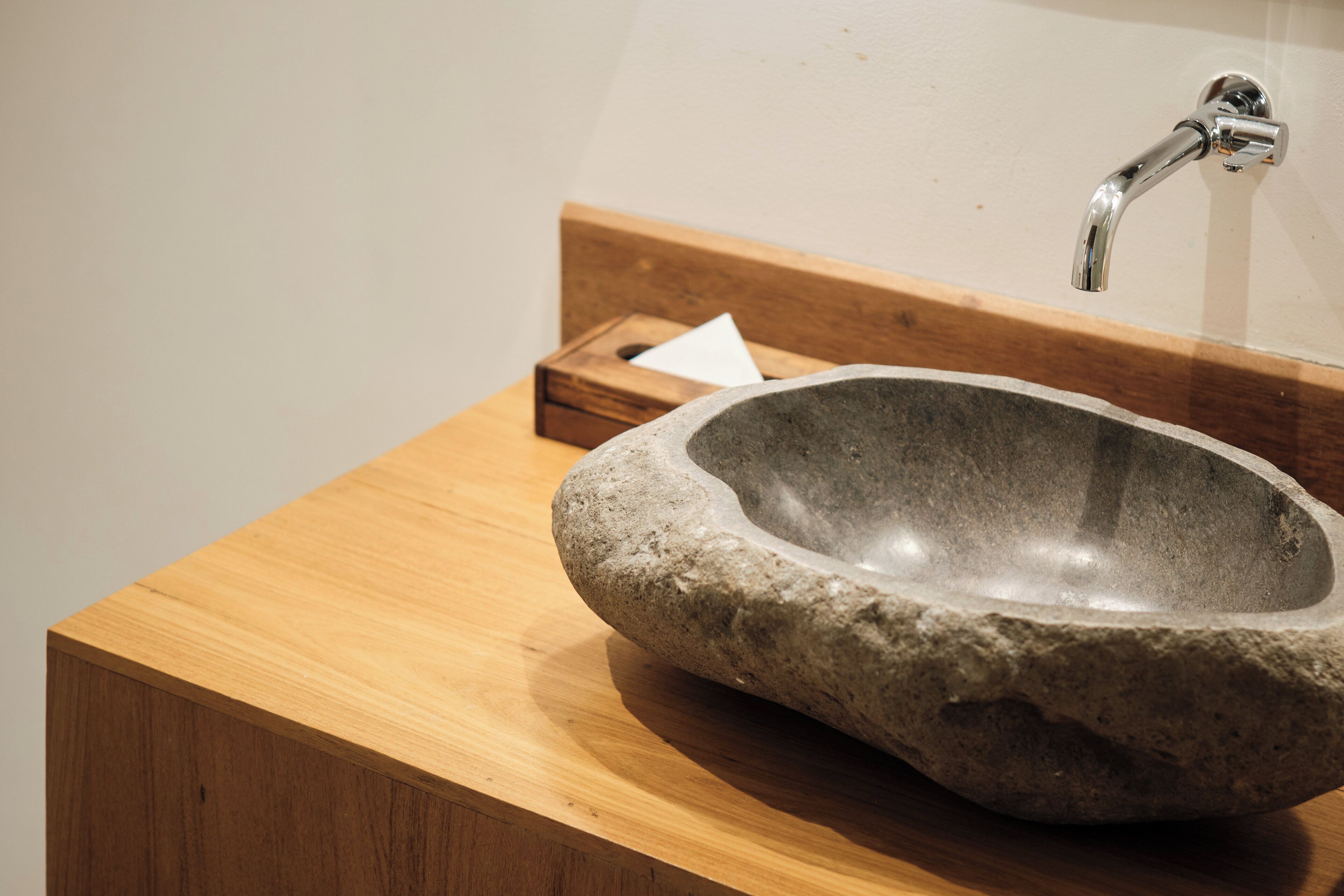 Ein Steinbecken mit einem Wasserhahn auf einer Holzauslage.