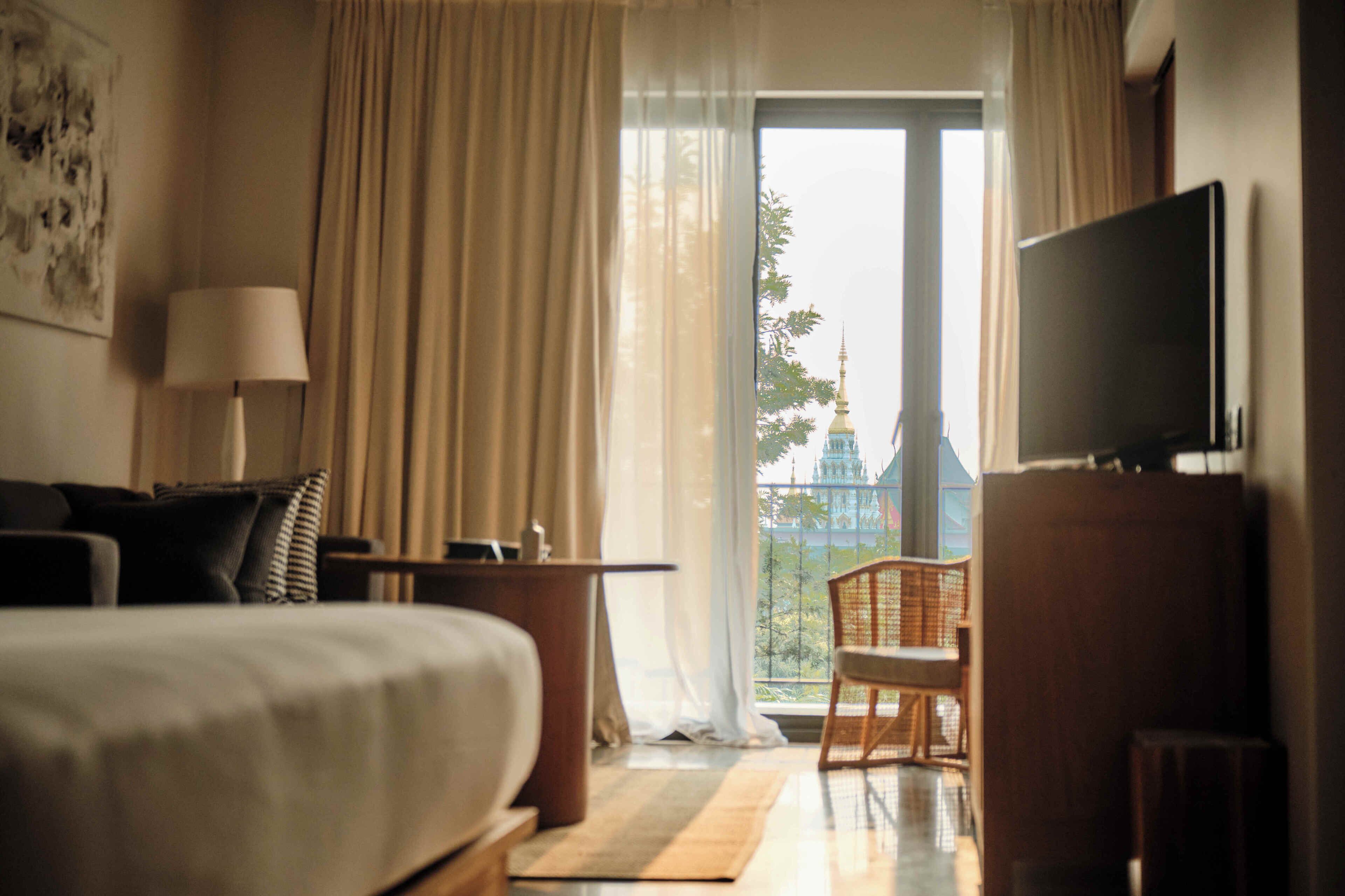 Une chambre d’hôtel avec un lit, un bureau, une chaise, un téléviseur et une vue sur un temple par la fenêtre.