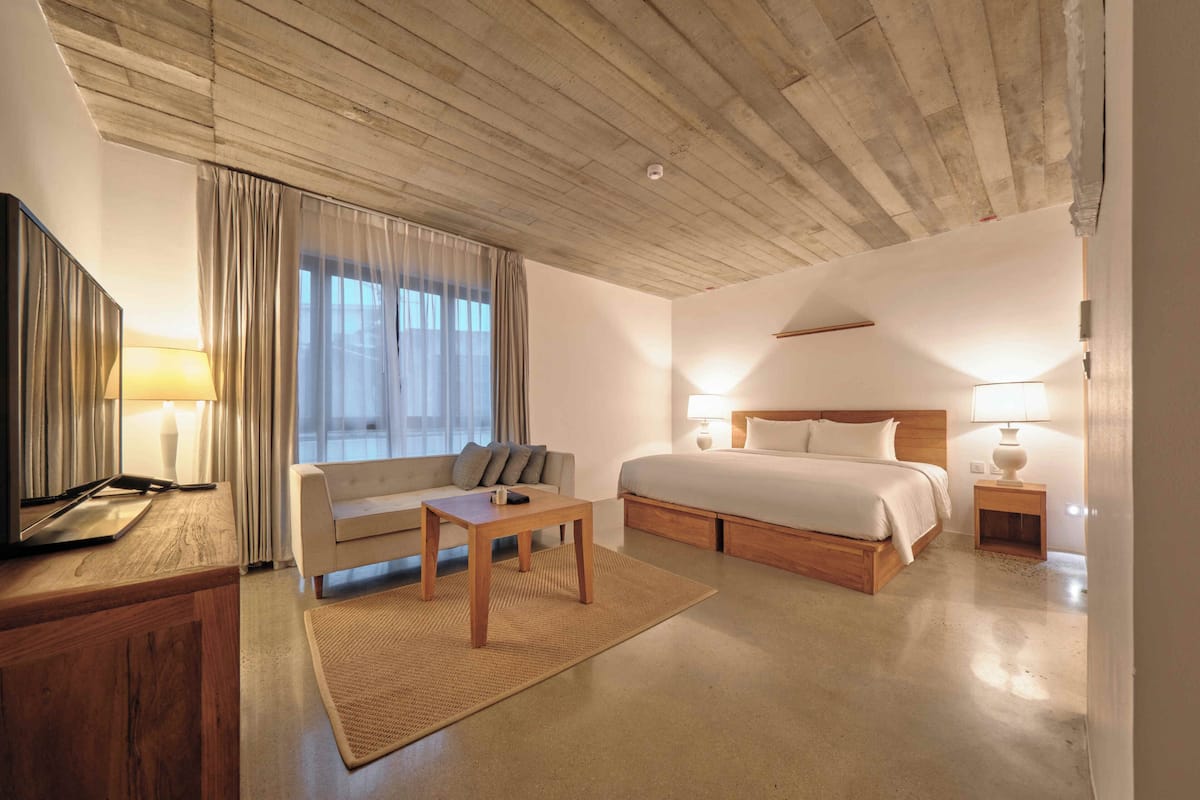 Ein Hotelzimmer mit Holzboden, einem Bett, einer Couch, einem kleinen Tisch und einem Fernseher.