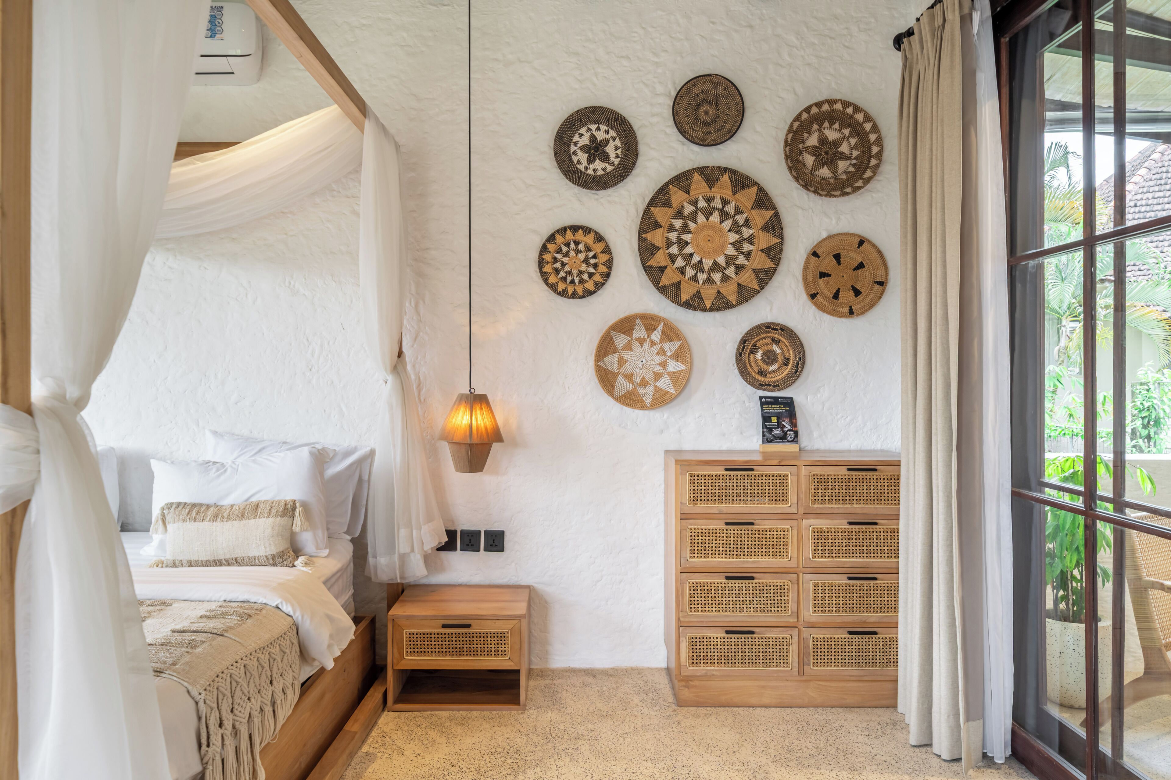 Una camera da letto con un letto a baldacchino, una lampada da comodino, una parete decorata con piatti e un mobile contenitore in legno.