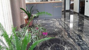 A modern kitchen with marble flooring, grey cabinets, and a decorative shelf with kitchenware. - ZANGEZUR HOTEL GORIS (Goris)