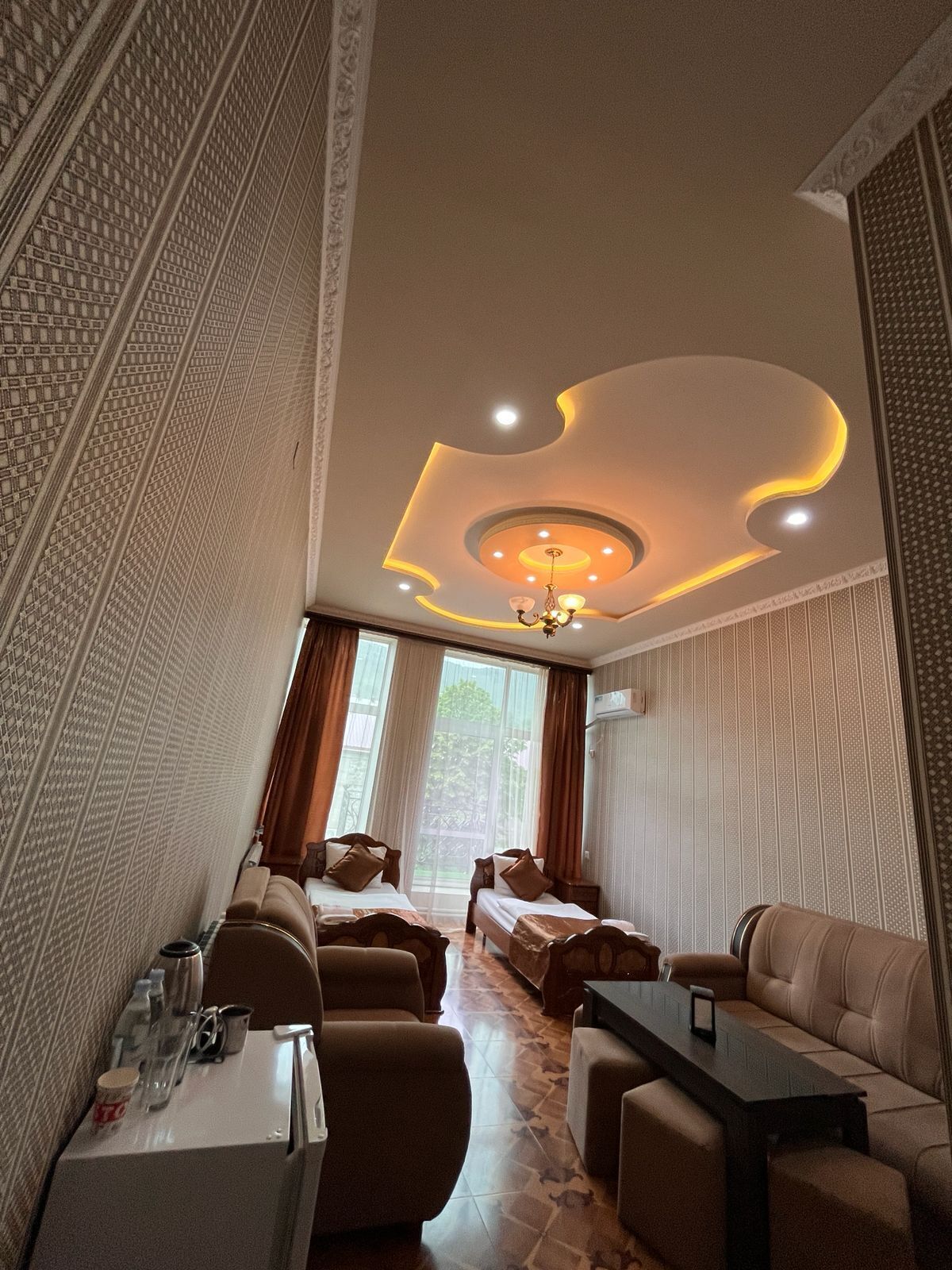 Une chambre d’hôtel comprenant un coin repas, deux lits, un canapé, une table et un lustre.