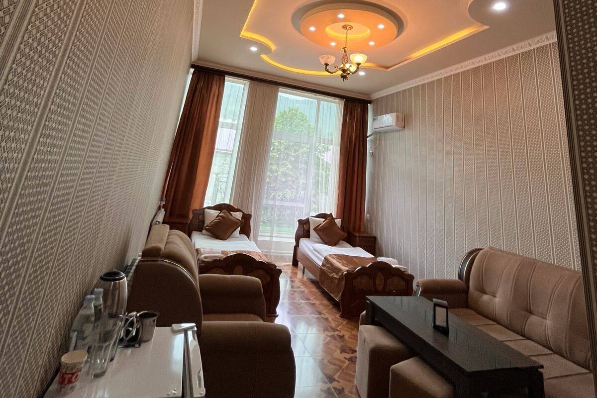 Une chambre dâhĂŽtel comprenant un coin repas, deux lits, un canapĂ©, une table et un lustre.