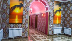 A hallway with patterned wallpaper, large sunset paintings, and a tiled floor. - ZANGEZUR HOTEL GORIS (Goris)