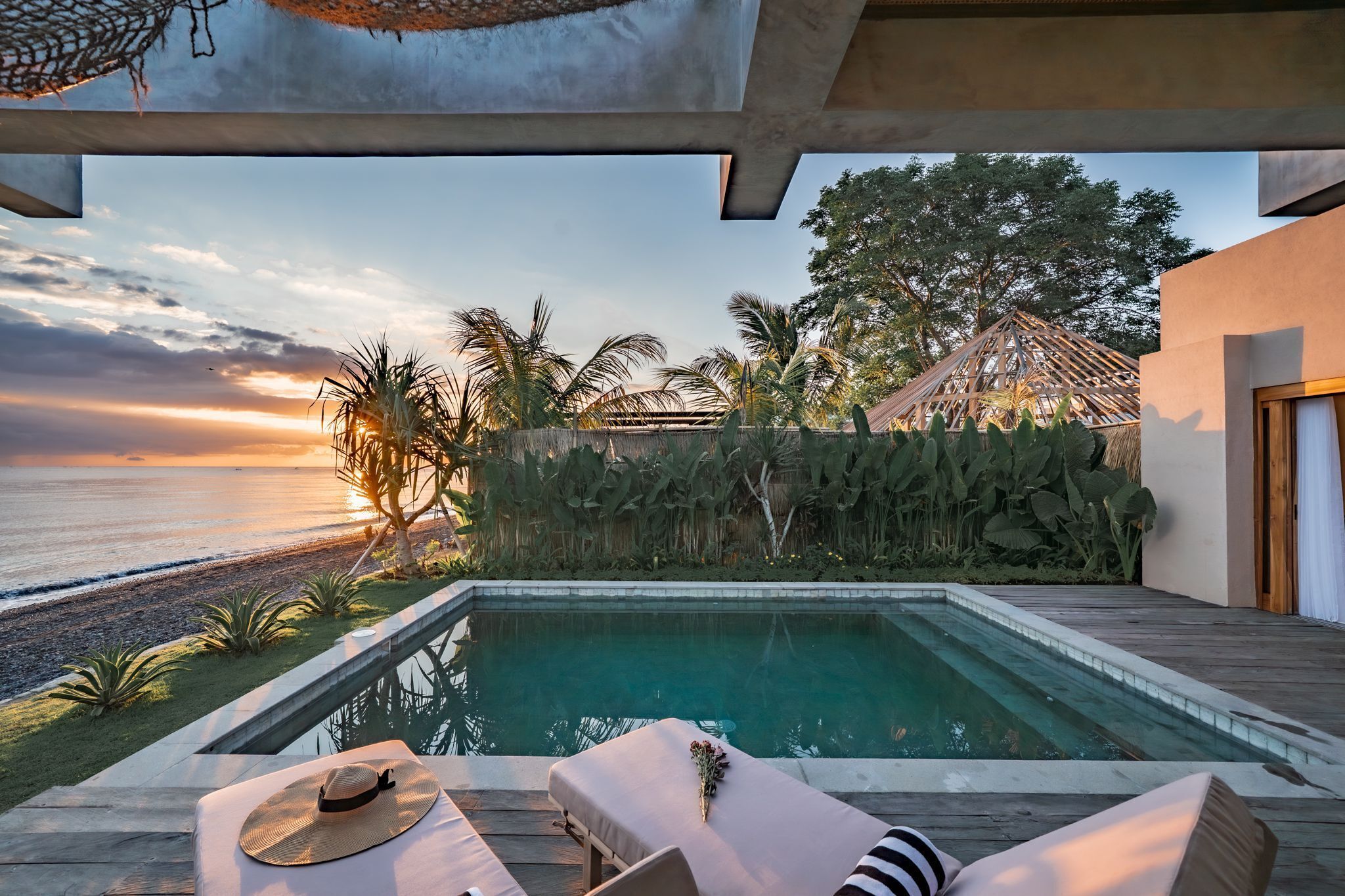 Ein Pool mit Liegestühlen, einem Hut und Blumen auf der Terrasse.