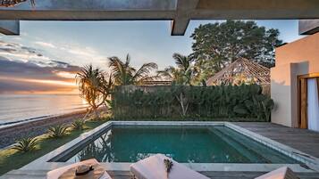 Ein Pool mit Liegestühlen, einem Hut und Blumen auf der Terrasse.