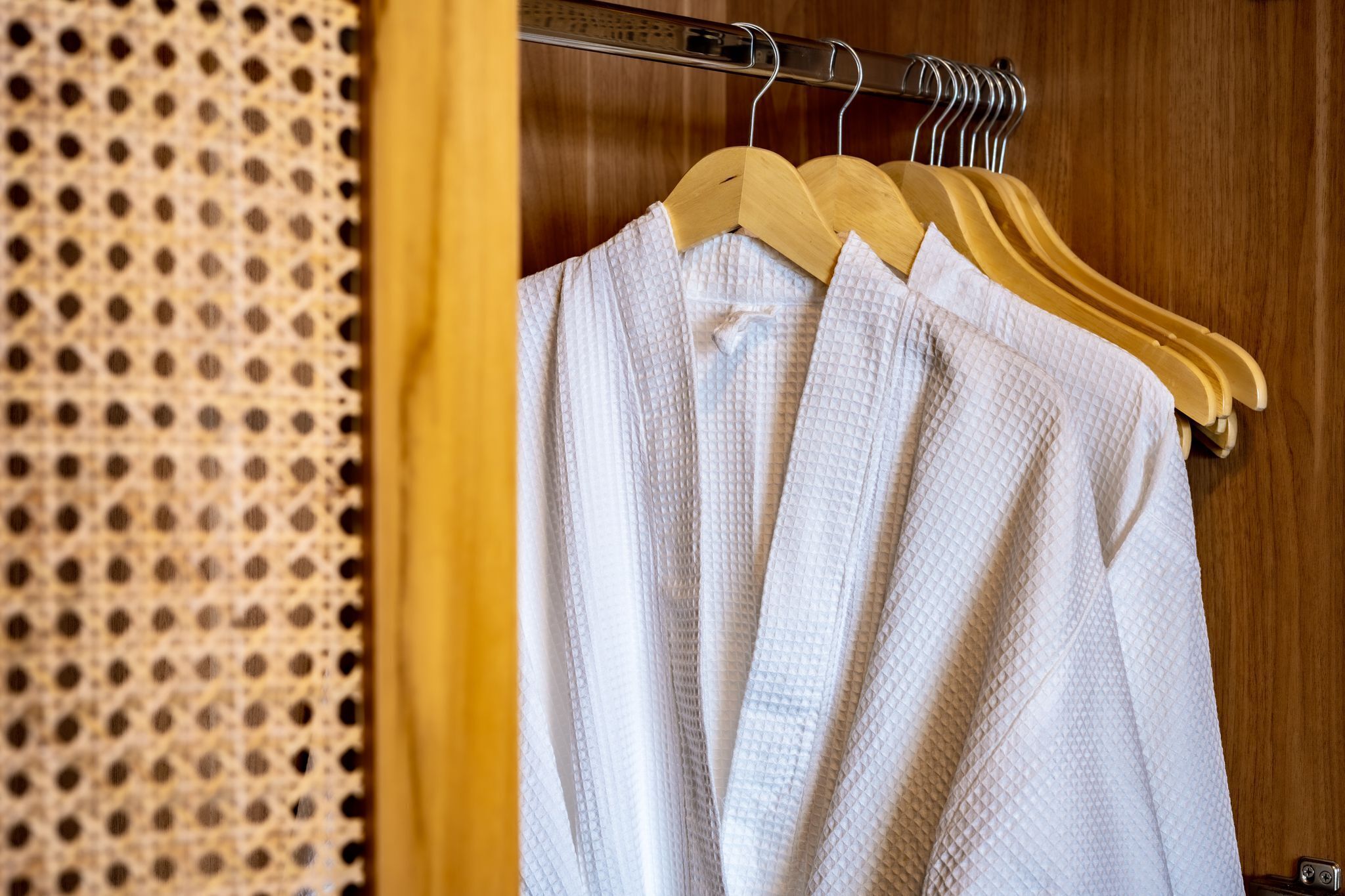 A wooden wardrobe with a hanging rod and a metal rack.